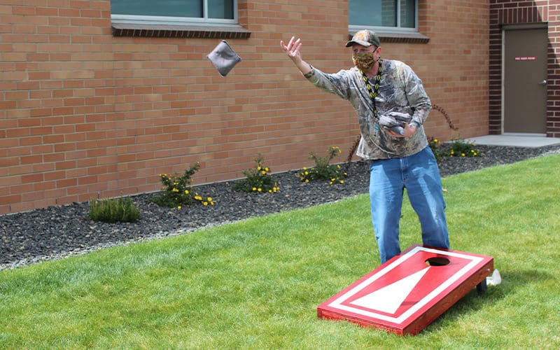 man playing cornhole outside