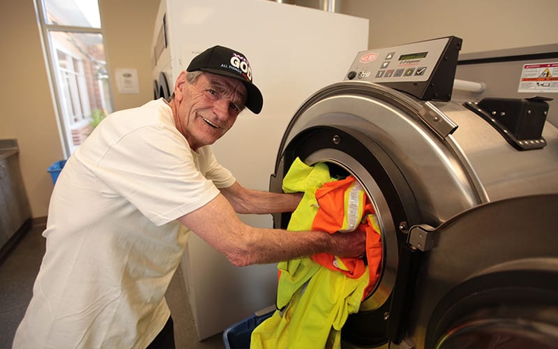 man loading laundry in a large washing machine at TCUGM